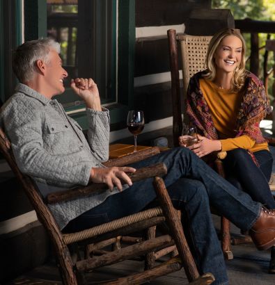 A Man And Woman Sitting On A Bench And Talking